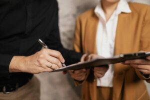 Gros plan de deux professionnels signant un document à l'intérieur, mise au point sur les mains et le stylo.