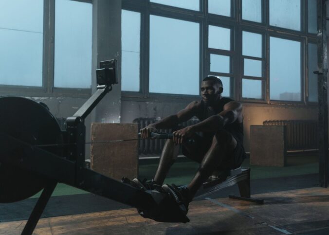 Un homme pratique le rowing sur un appareil dans une salle lumineuse