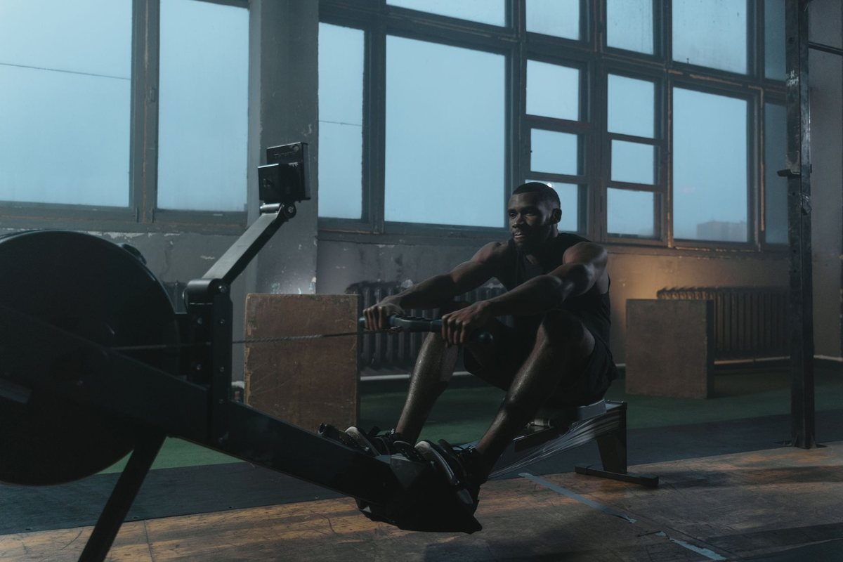 Un homme pratique le rowing sur un appareil dans une salle lumineuse