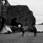 Tentes blanches dressées face aux ruines imposantes d'un château médiéval