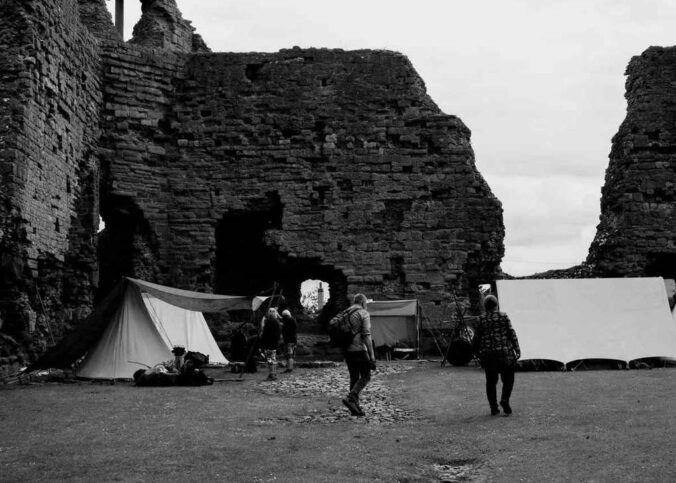 Tentes blanches dressées face aux ruines imposantes d'un château médiéval