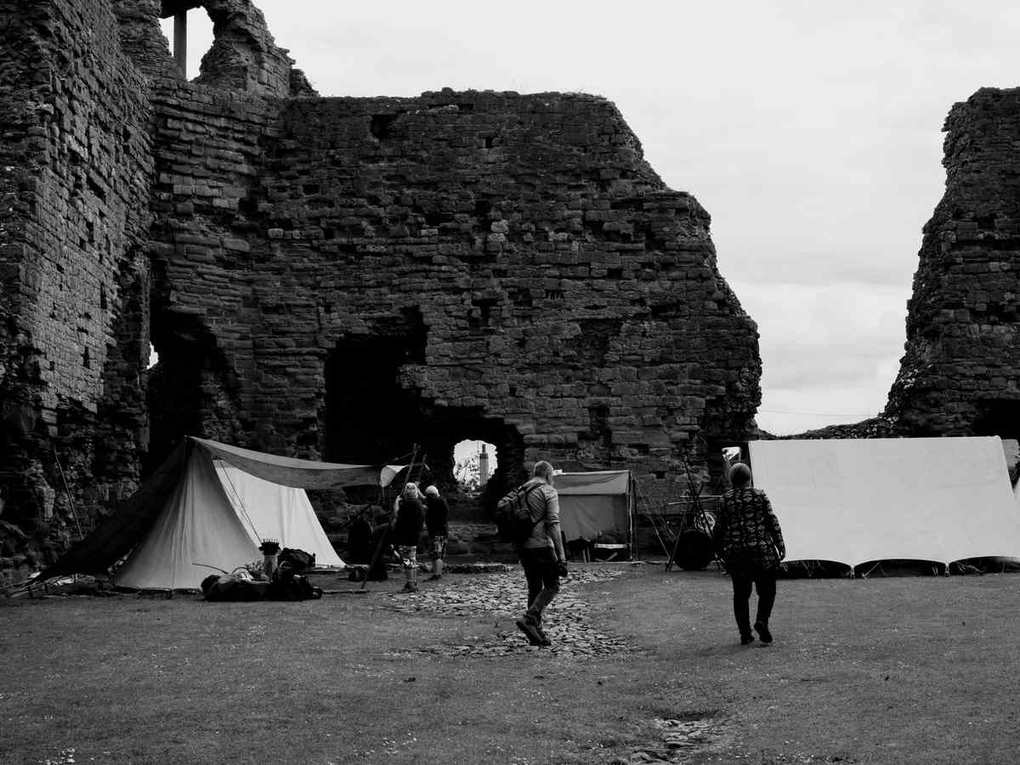 Tentes blanches dressées face aux ruines imposantes d'un château médiéval
