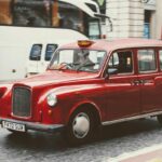 Taxi londonien rouge circulant en rue urbaine avec plaque de taxi éclairée
