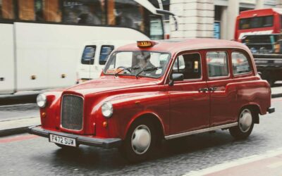 Taxi londonien rouge circulant en rue urbaine avec plaque de taxi éclairée