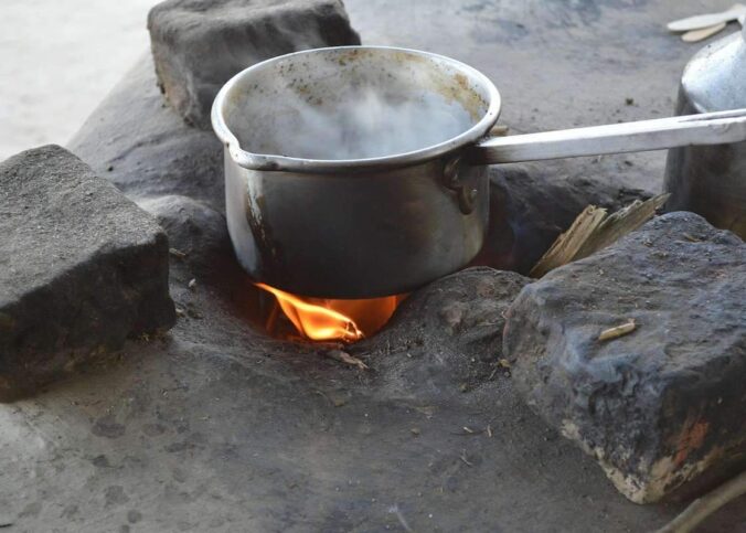 Casserole d'eau chauffée sur un feu de camp avec pierres et brindilles, en extérieur