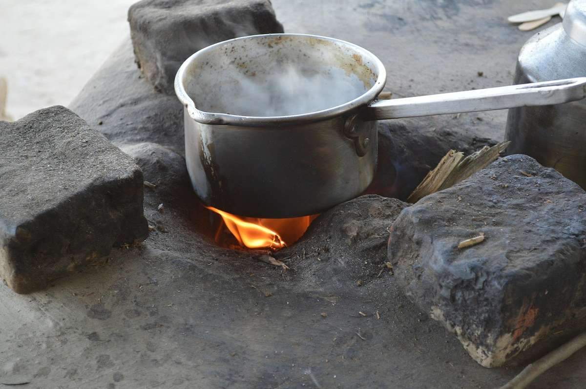 Casserole d'eau chauffée sur un feu de camp avec pierres et brindilles, en extérieur