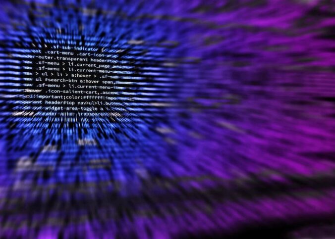 Écran d'ordinateur flou affichant du code informatique en arrière-plan violet