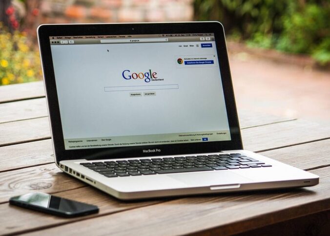 Un ordinateur portable affiche la page Google sur une table en bois