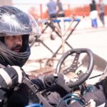 Un conducteur en casque noir pilote un kart sur circuit extérieur